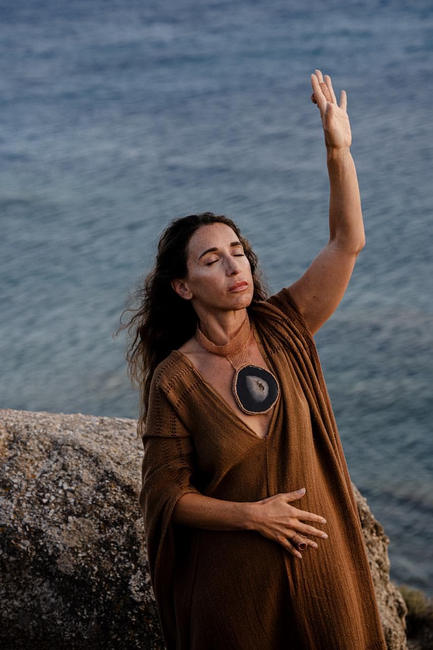 Jennifer reaching toward the ocean, eyes closed in presence